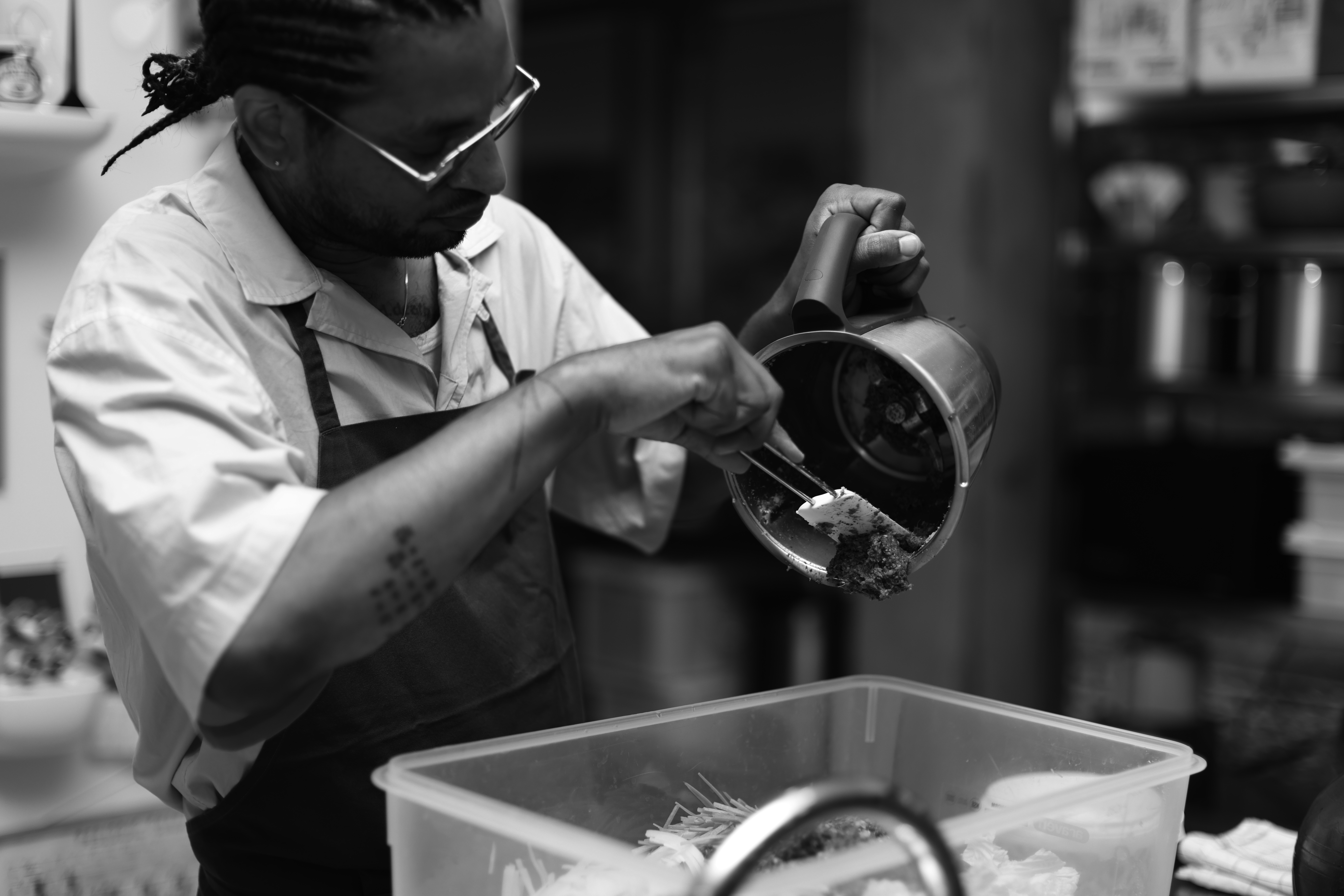 A black and white photograph of a chef working in the kitchen, an image by David Zilber